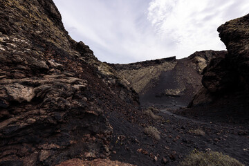 scenery view of volcano Cuervo and rough mountains under cloudy sky in Tinajo, Lanzarote at Canary Islands, Spain, concept of volcanic landscape