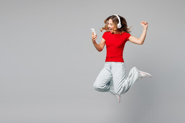 Full body young smiling happy woman she wear red t-shirt casual clothes jump high listen to music...