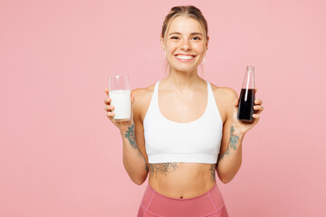 Young fun woman wear white top casual clothes choose hold glass of milk, bottle of soda pop...