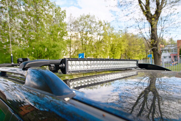 Closeup of an LED light bar installed on the roof of an off-road vehicle, reflecting trees on the glossy surface. LED light bar mounted on a car's roof © Tricky Shark