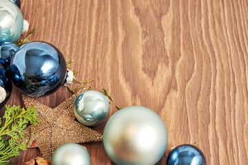Close-up of blue and green Christmas ornaments arranged on a wooden background. The ornaments are shiny and reflect the light with festive atmosphere