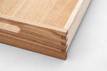 Solid ash wood tray with dovetail joints and cutout handles on the sides for easy carrying closeup view on white background