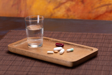 Wooden tray with water and assorted pills for daily health routine