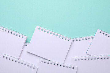 Group of Blank white spiral notebooks on mint green background with copy space