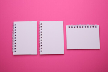 Group of white blank spiral notebooks on pink background