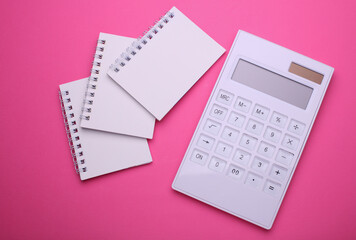 Group of Blank white spiral notebooks with calculator on pink background