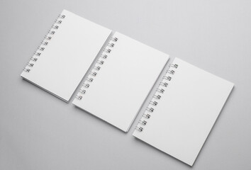 Group of white blank spiral notebooks on gray background