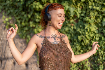 Happy woman in headphones dancing in park