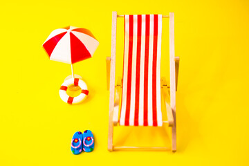 Red hammock with flip flops, umbrella and float next to it on a yellow background