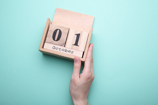 Hand holding wooden block calendar with date october 23 on mint green background