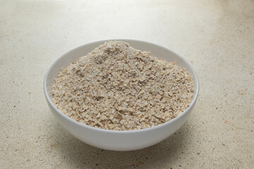 You can see the top corner of full oats in a clean white bowl on the table