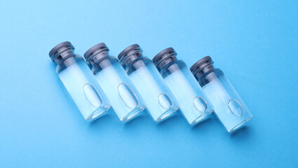 Medical glass vials with liquid on a blue background