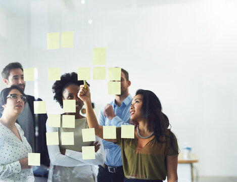 Idea, brainstorming and business people in office for meeting, discussion and task schedule on glass wall. Creative, startup and workers with sticky notes for teamwork, research and group project