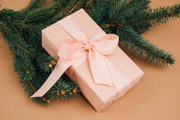 Christmas, festive background. Rose gift box with pink ribon on green coniferous branches on a brown background. Top view