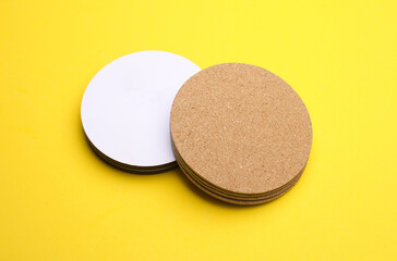 Cork and white coasters for drinks on a yellow background