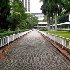 Fototapeta premium A peaceful path through a lush green park surrounded by tall buildings in the afternoon