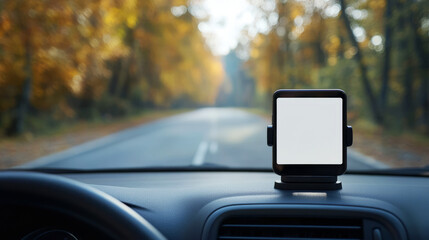 A smartphone mounted on a car dashboard, with a scenic road lined by autumn trees in the background.
