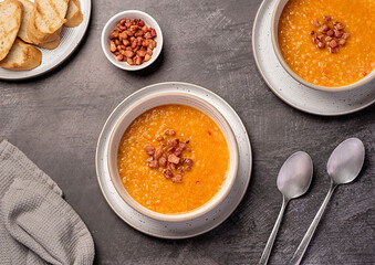 Food photography of red lentil soup with chili and bacon, carrot, onion, garlic, toasted bread, broth, stock, set table
