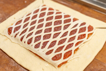 Making a pie with apple jam. A square of dough on which a fruit filling is laid out, covered with a mesh of dough. Prescription