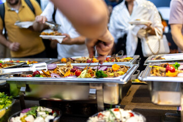 People enjoying a buffet with diverse food selections at a lively event in an indoor venue during the evening hours