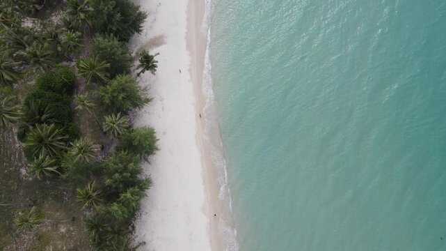 Top view of woman in swimsuit walking alone on the beach.Green sea water, white sand beach, green forest on the shore thailand
