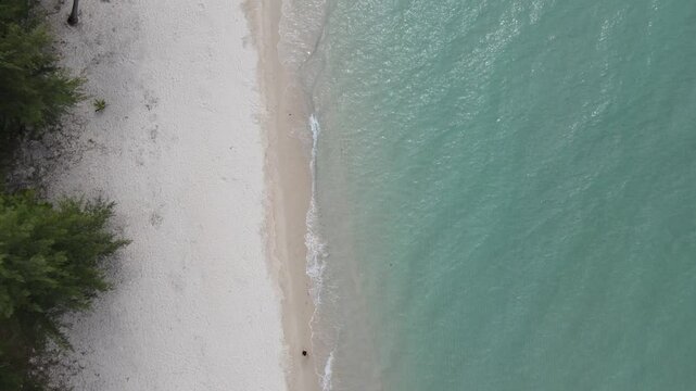 Top view of woman in swimsuit walking alone on the beach.Green sea water, white sand beach, green forest on the shore thailand