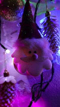 Una toma de cerca de una decoraci&oacute;n de navidad y fin de a&ntilde;o con una cara de santa claus  rodeado de varias luces con bombillos de varios colores en movimiento en la oscuridad. Video Vertical