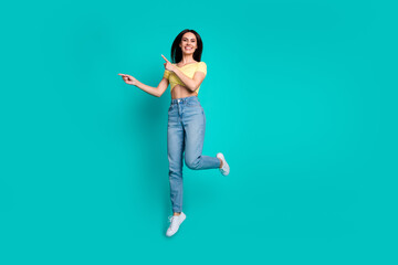 Full size photo of pretty young woman jump direct fingers empty space wear top isolated on teal color background