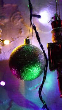 Una toma de cerca de un soldadito de juguete rodeado de bolas de navidad y luces de colores. Decoraci&oacute;n de navidad y fin de a&ntilde;o.Video vertical.