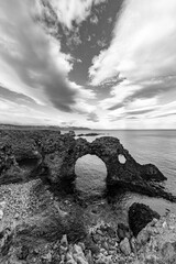 Gatklettur natural arch or bridge on the coast of Sn&aelig;fellsnes peninsula Iceland near Arnarstapi village. Landscape wilderness with volcanic rock cliffs, seabird nests in contrasting black and white.