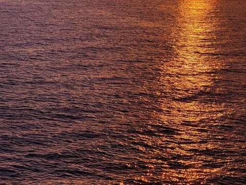 Ocean golden shiny waves at sunset background