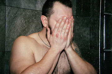 Attractive man cries in the shower. Depression and despair.