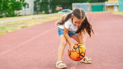 Fototapeta premium Little girl playing with a soccer ball on outdoor sports fields