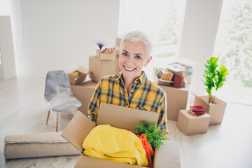 Photo of nice aged woman good mood hold box wear checkered shirt relocate move new apartment indoors
