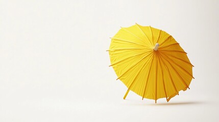 A yellow cocktail umbrella stands alone against a pure white background. Its vibrant hue and cheerful design add a touch of whimsy to the otherwise stark surroundings