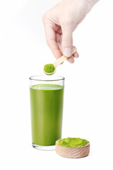 Woman's hand holds a wooden spoon with powder of Wheat grass, detox superfood, energy drink, isolated on white background vertical food