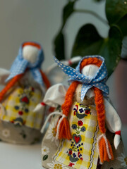 Two traditional Ukrainian motanka dolls with light blue headscarves and two long red braids each, standing side by side