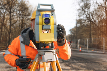 Surveyor at Work Measuring Land With a Total Station in a Construction Area on Clear Day