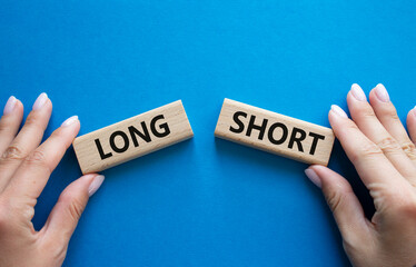 Short vs Long symbol. Concept word Short vs Long on wooden blocks. Businessman hand. Beautiful blue...