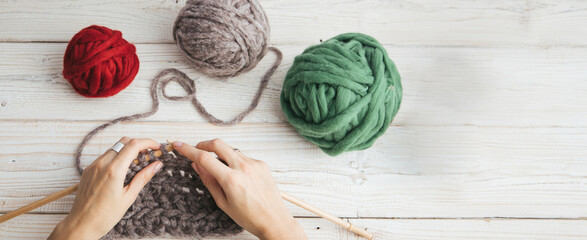 knitting crochet  woman hands top view. three balls of yarn gray, green and red. Relaxing hand craft hobby time. Long horizontal banner
