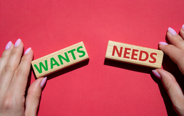 Wants and Needs symbol. Concept word Wants and Needs on wooden blocks. Businessman hand. Beautiful red background. Business and Wants and Needs concept. Copy space