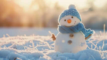 Obraz premium Cute snowman with blue scarf and hat sitting in snowy field, soft blurred background,perfect for Christmas and seasonal designs, holiday cards, and winter-themed marketing materials. 