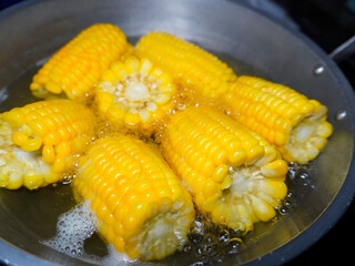 the process of cooking corn on the cob by soaking the corn in boiling water until cooked