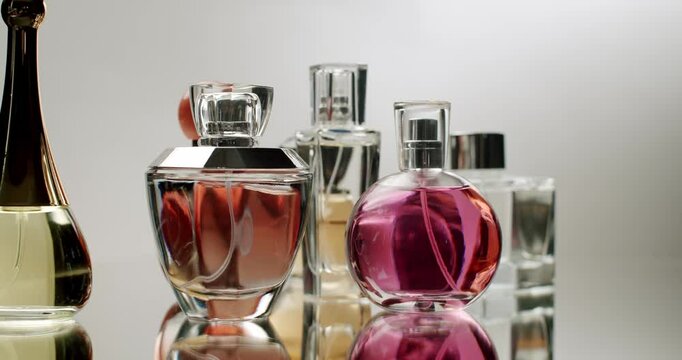 Close-up of various elegant perfume bottles displayed on a reflective surface, highlighting luxurious scents and stylish packaging. Ideal for beauty and glamour themes.