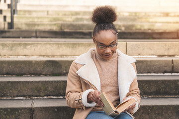 Obraz premium Young Woman Enjoys Reading on Peaceful Stone Steps in Sunlit Outdoor Setting