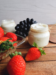Pot of natural yogurt with fruits and a light background. Vertical photo