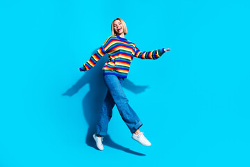 Full size photo of pretty young girl running shopping wear trendy striped outfit isolated on blue color background