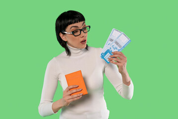 Excited Traveler Checks Flight Tickets While Holding Luggage on Bright Green Background