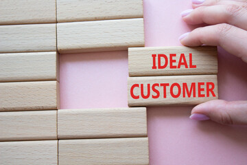 Ideal Customer symbol. Wooden blocks with words Ideal Customer. Businessman hand. Beautiful pink background. Business and Ideal Customer concept. Copy space.