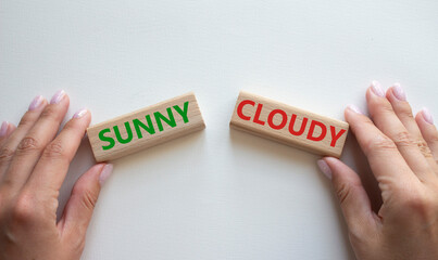 Sunny or Cloudy symbol. Concept word Sunny or Cloudy on wooden blocks. Businessman hand. Beautiful white background. Business and Sunny or Cloudy concept. Copy space